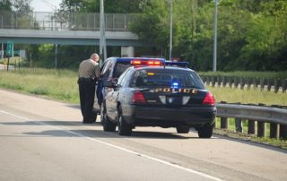 Traffic Ticket Police Vehicle - A police cruiser with the lights flashing has stopped a speeding car along the interstate highway and is issuing a ticket.